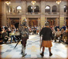 armoured knight speaking to audience in magnificent hall